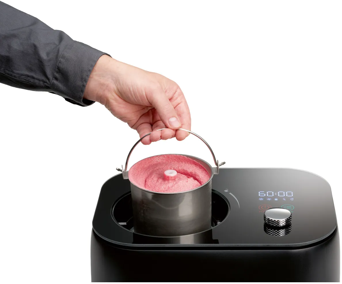 Una mano tiene un contenitore di gelato rosa. È inserito in una macchina nera con un display digitale che mostra 60:00.