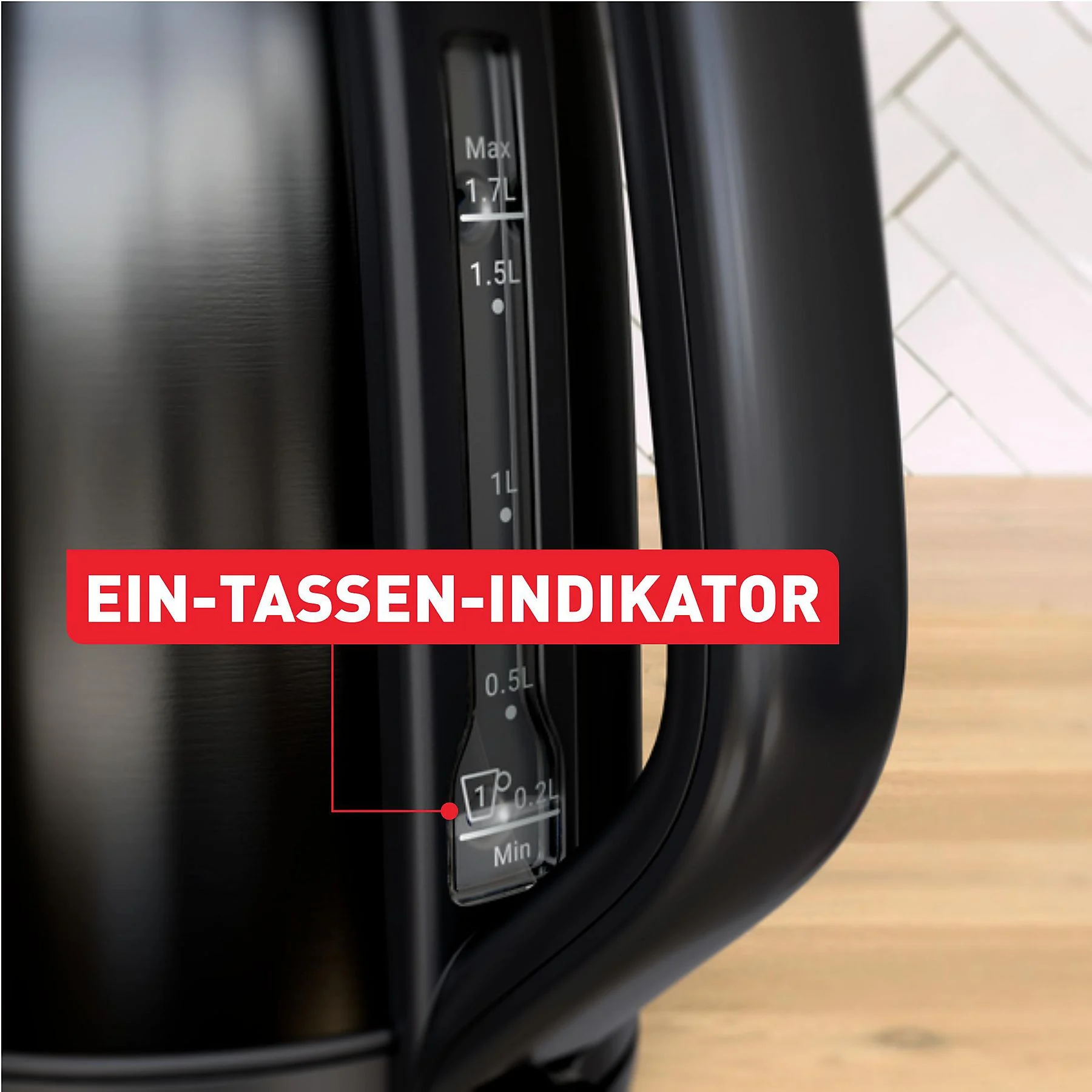 Nahaufnahme eines schwarzen Wasserkochers mit Wasserstandsanzeige. Ein rotes Schild sagt 'EIN-TASSEN-INDIKATOR'.