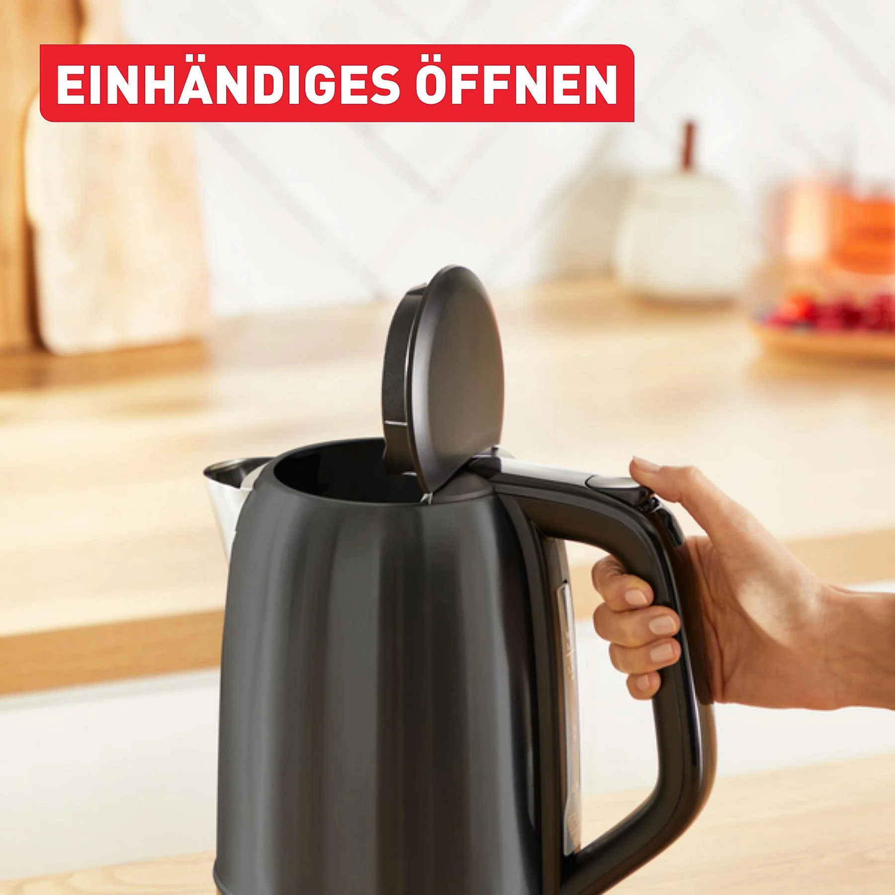 Ein schwarzer Wasserkocher mit offenem Deckel, gehalten von einer Hand. Ein rotes Banner mit der Aufschrift 'EINHÄNDIGES ÖFFNEN'.