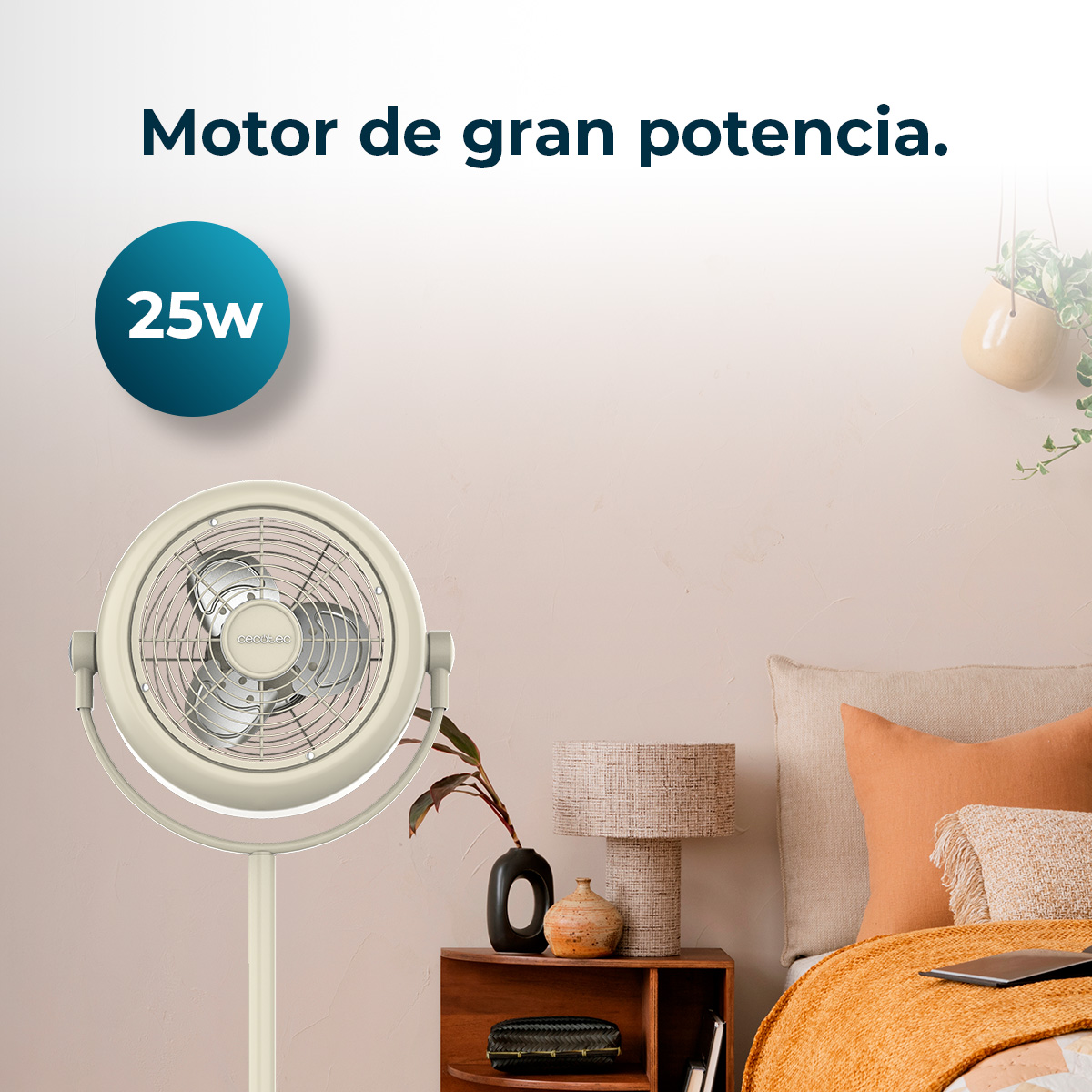 Un ventilador beige con una etiqueta de 25W, en un dormitorio. Hay una cama con almohadas naranjas y una mesita de noche.