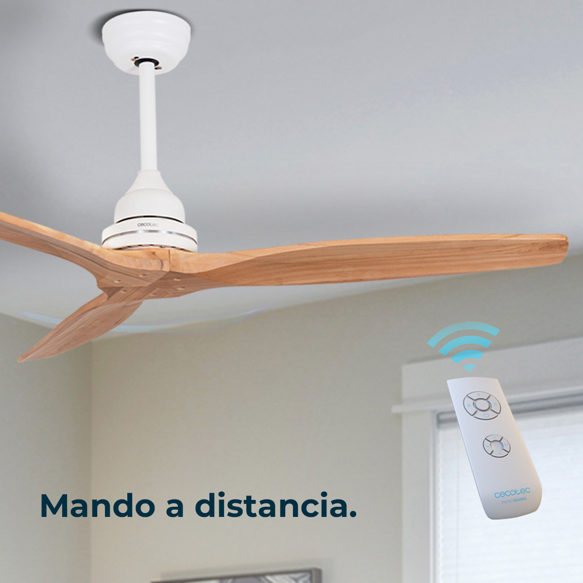 Un ventilador de techo con aspas de madera se controla con un mando a distancia. El ventilador es blanco y el mando también con iconos azules.