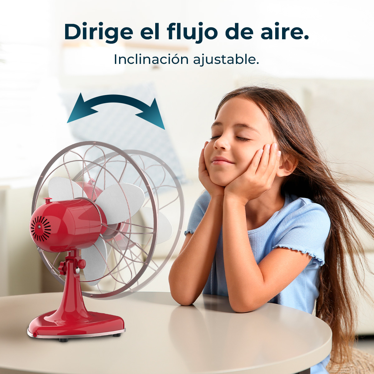 Una niña disfruta la brisa de un ventilador rojo. El ventilador está sobre una mesa. La niña sonríe con los ojos cerrados.