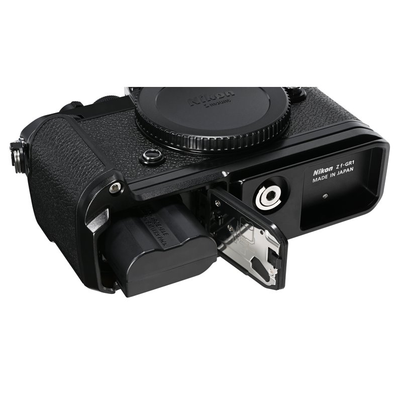 Cámara Nikon Z f-GR1 negra con compartimento de batería abierto. Batería negra visible. La tapa del objetivo está puesta.
