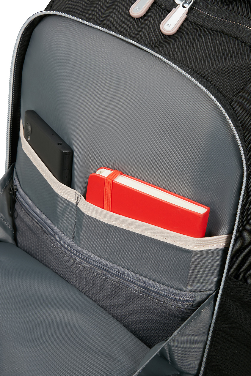 Czarny smartfon i czerwony notatnik w kieszeni plecaka.