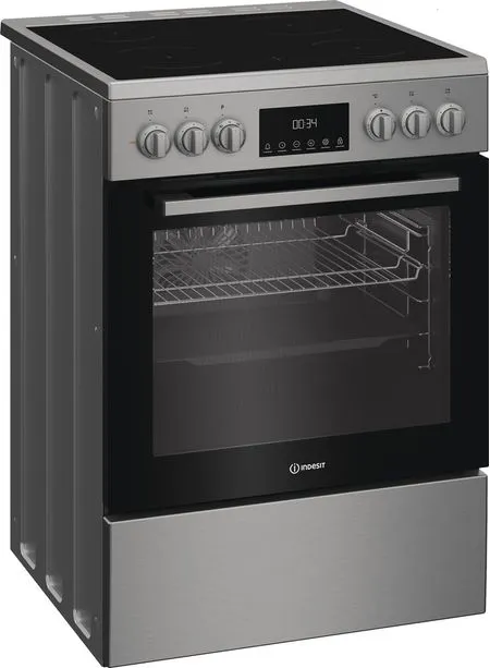 Un four Indesit argenté avec une porte vitrée noire. Il possède une horloge numérique, des boutons et une plaque de cuisson noire.