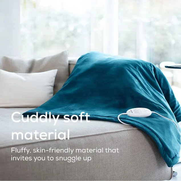 Una coperta turchese è drappeggiata su un divano. I cuscini sono sullo sfondo. Un pannello di controllo bianco è sulla coperta.