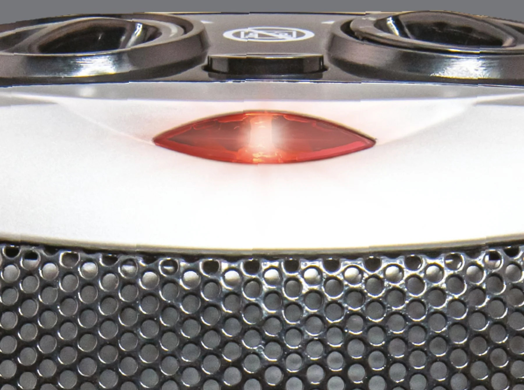 Zbliżenie urządzenia. Ma czerwone światło, metalową siatkę i dwa ciemne, okrągłe elementy u góry.