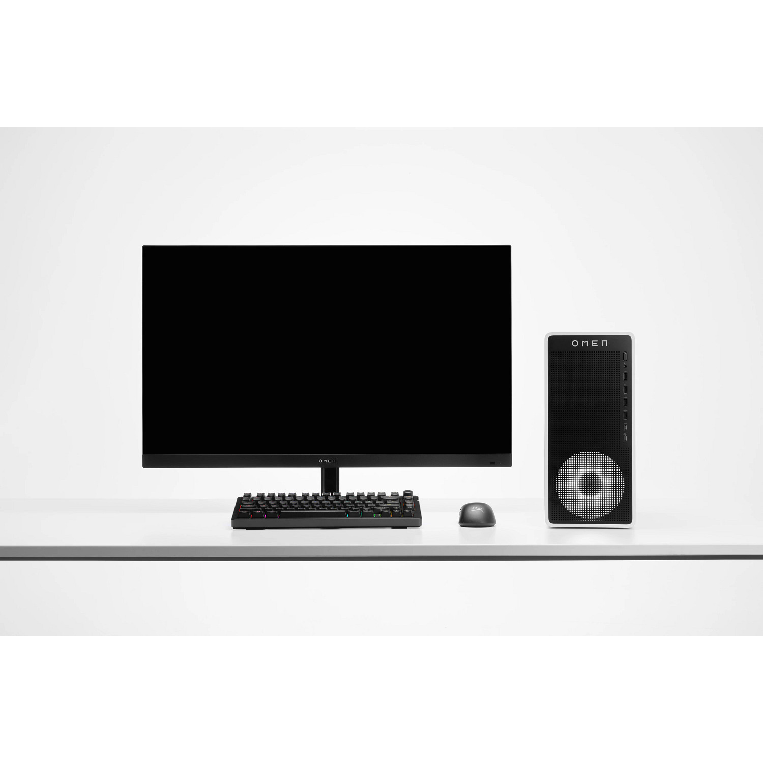 Een zwarte computermonitor, toetsenbord, muis en toren staan op een wit bureau.