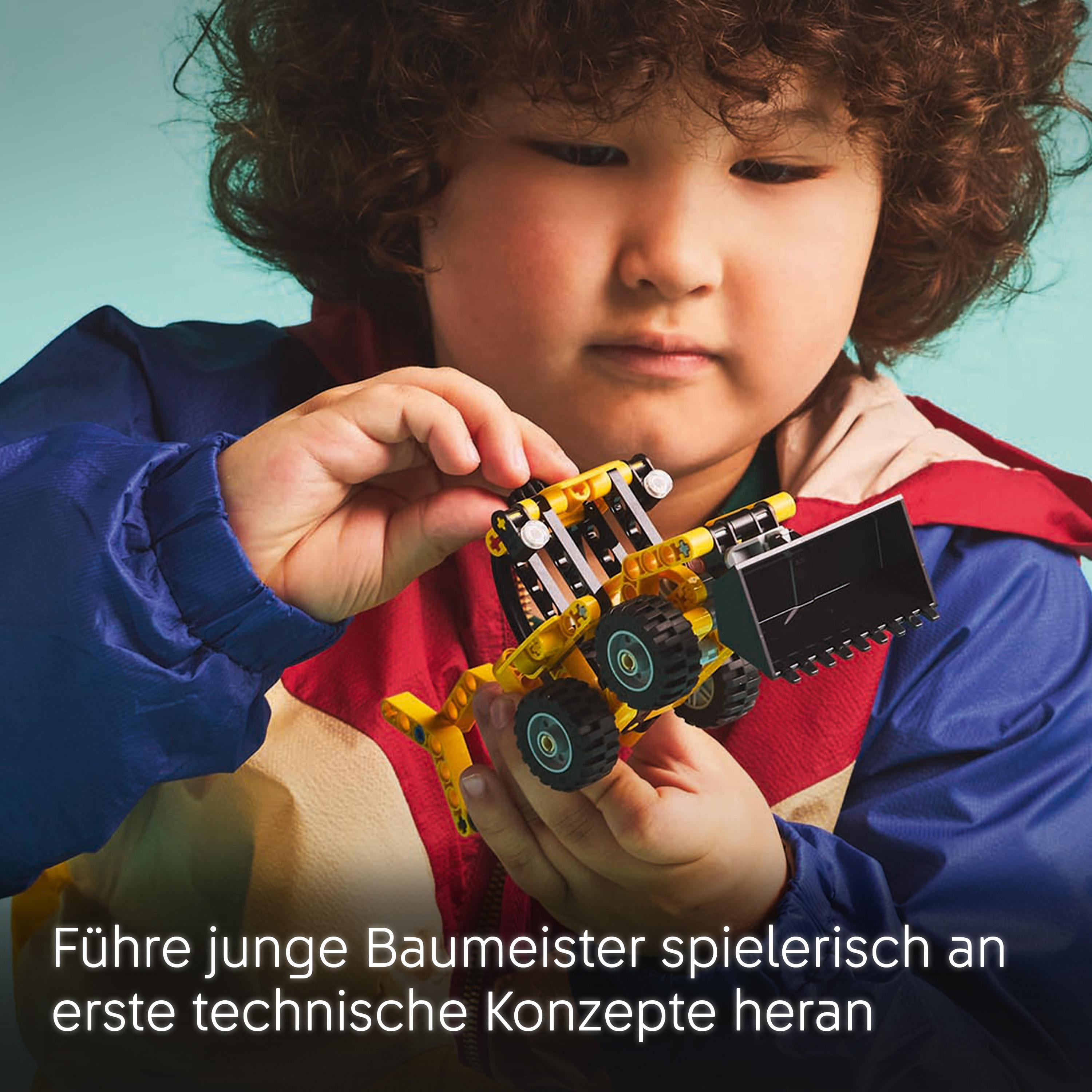 Ein Kind baut einen gelben Bagger aus Legosteinen.