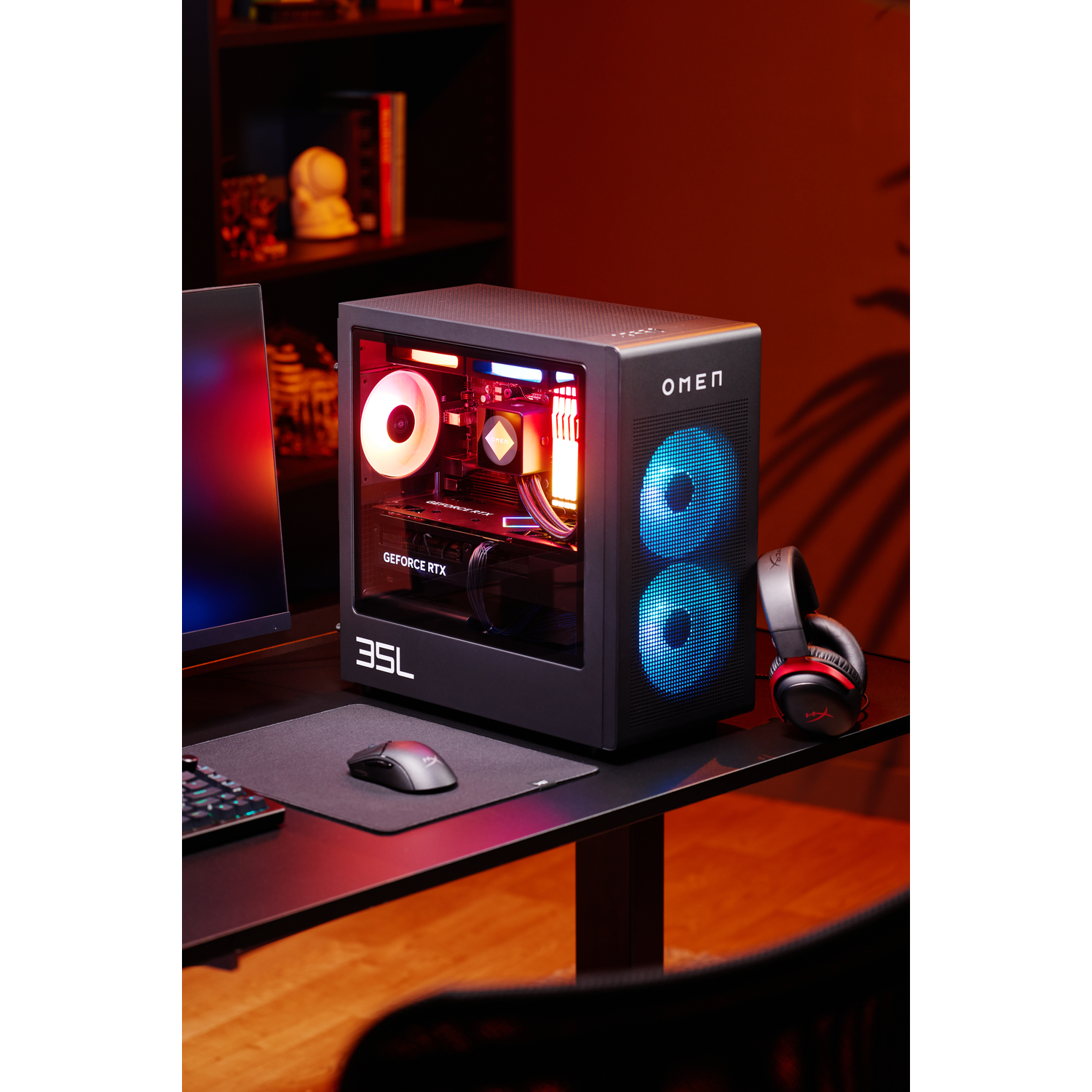 Een zwarte OMEN gaming-pc met RGB-verlichting, koptelefoon, muis en toetsenbord op een bureau.