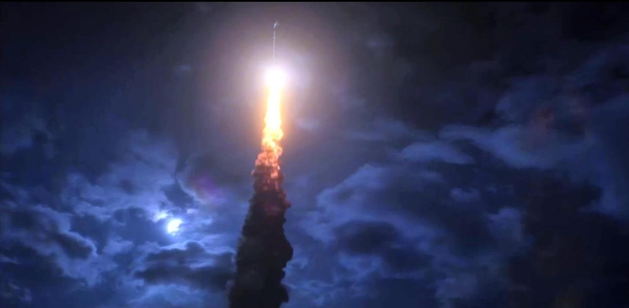 Eine Rakete startet in einen dunklen, bewölkten Himmel und hinterlässt eine Spur aus leuchtend orangefarbenem Feuer und Rauch.