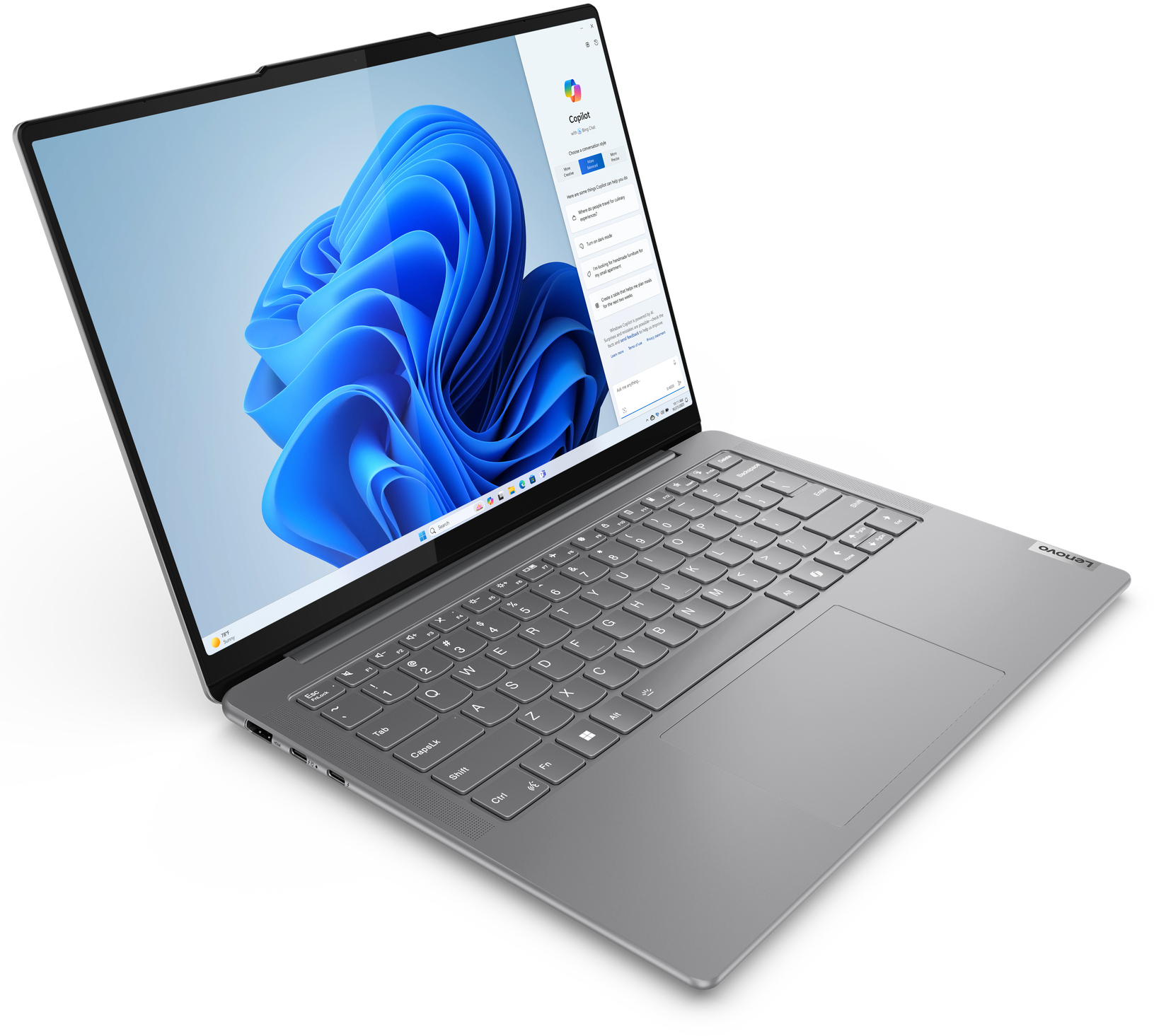 Un ordinateur portable Lenovo argenté est ouvert, affichant un fond d'écran bleu Windows 11 et le chat IA Copilot.
