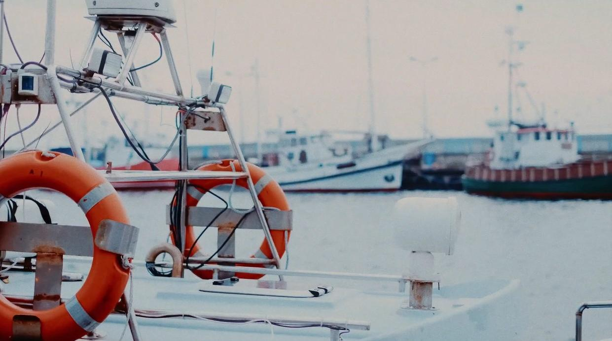 Orange Rettungsringe auf einem Boot, mit anderen Booten im Hafen.