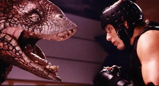 Eine reptilienartige Kreatur mit offenem Maul blickt auf einen Boxer mit Helm und Handschuhen.