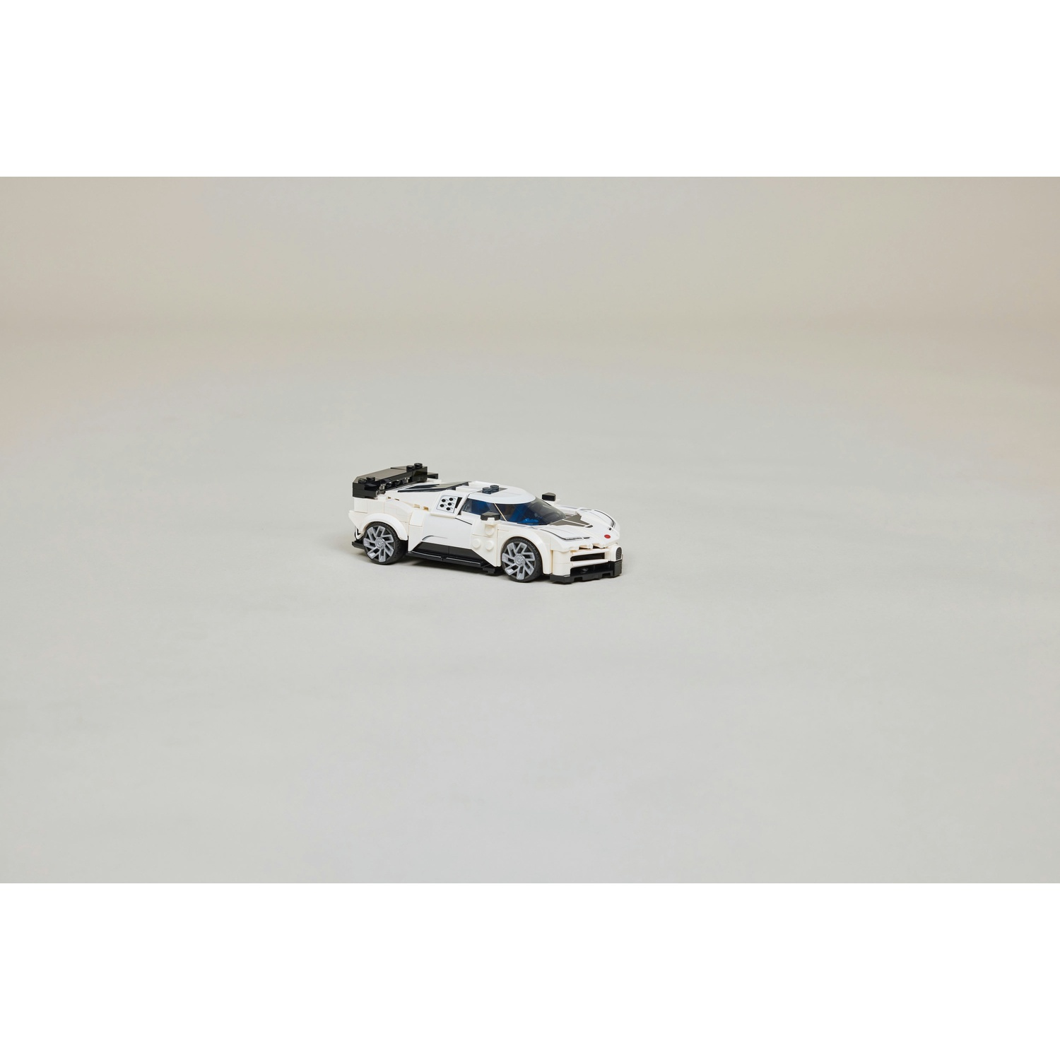 Una Bugatti Chiron hypercar bianca Lego con accenti neri è esposta su uno sfondo semplice.