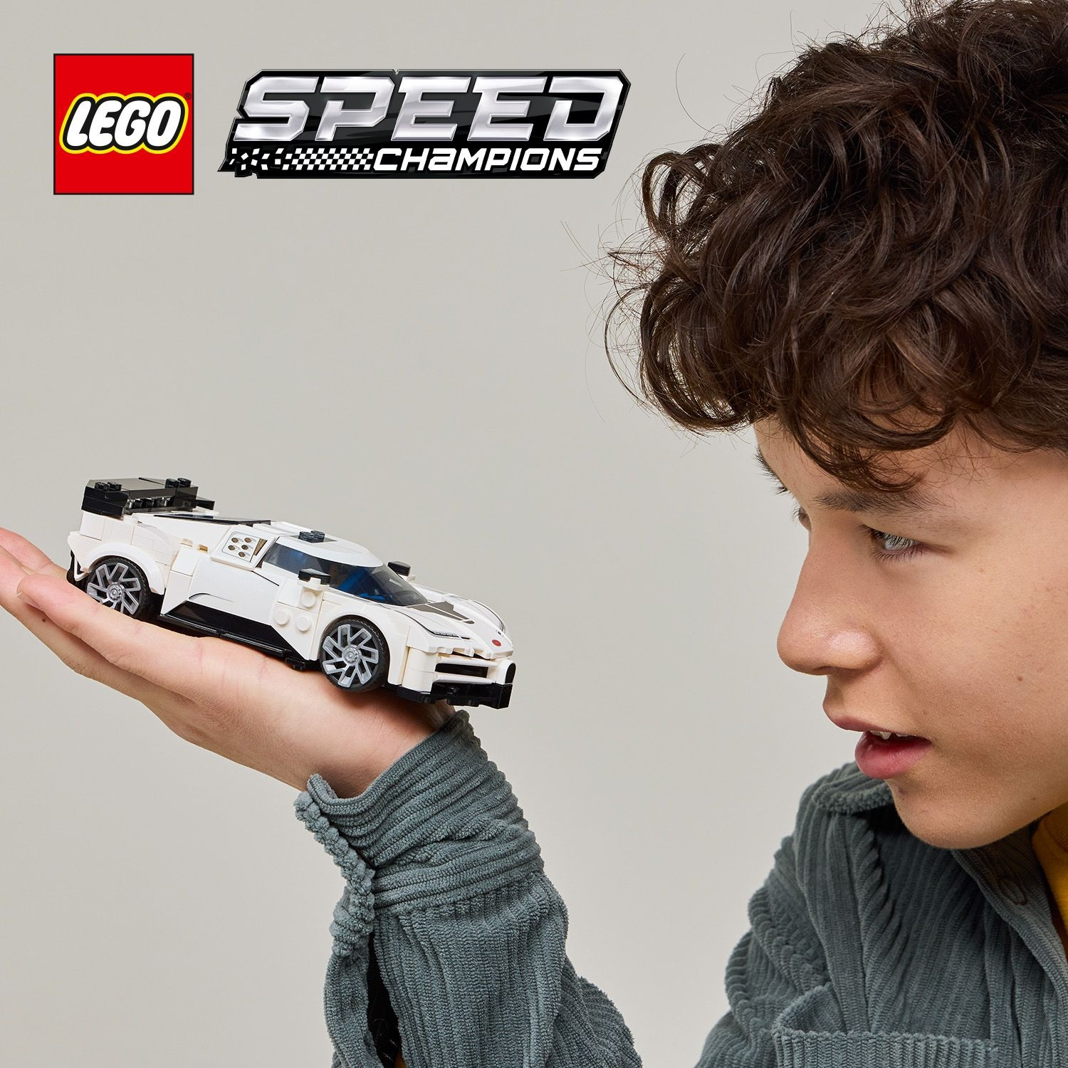 Un ragazzo tiene un'auto bianca Lego Speed Champions. Il logo Lego è visibile.