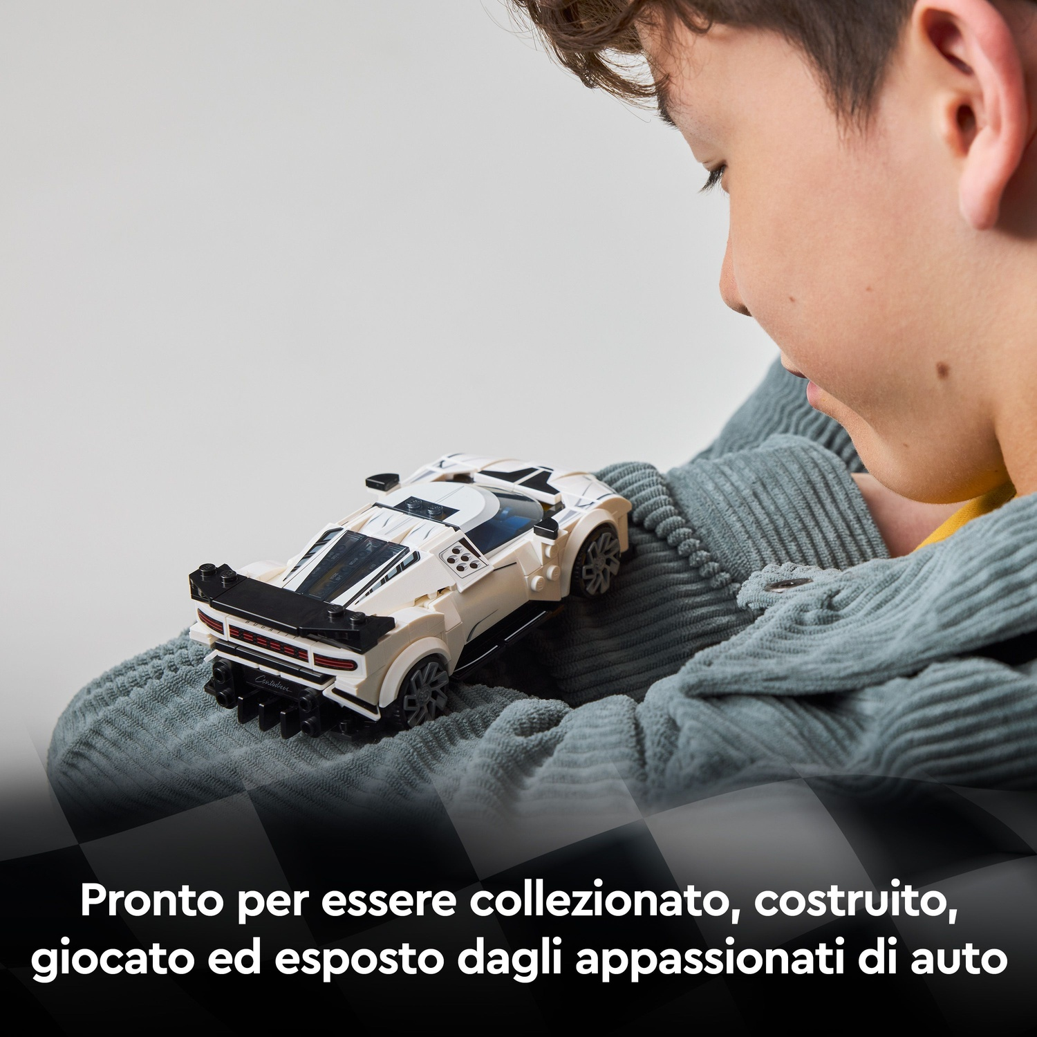 Un ragazzo tiene in mano un'auto Lego bianca e nera.