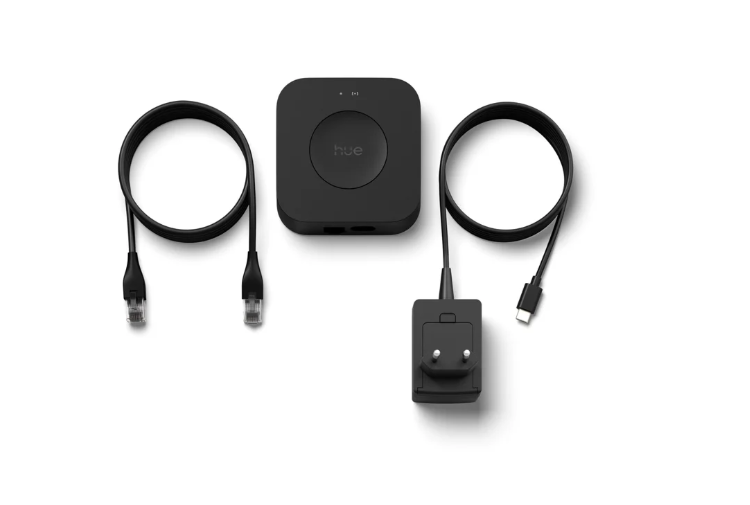 Un concentrador Hue negro con dos cables y un adaptador de corriente sobre fondo blanco.