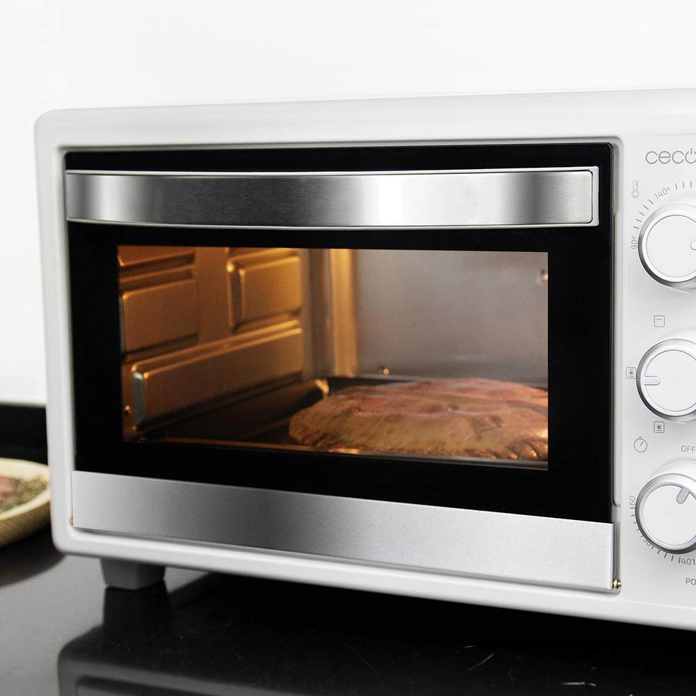 Un horno blanco con un alimento horneado dentro, visto a través de la puerta de cristal. Controles a la derecha.