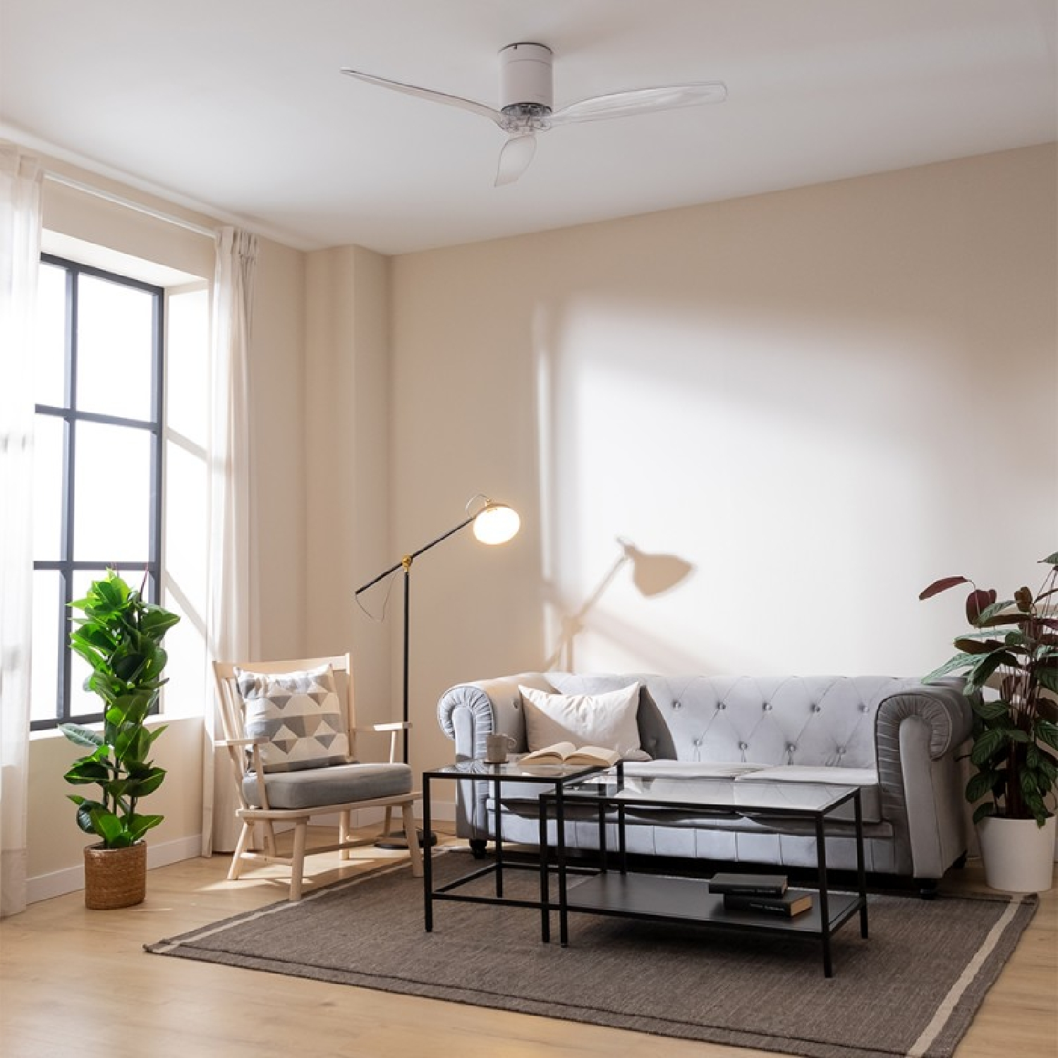 Una sala de estar con un sofá gris tapizado, un sillón de madera y dos mesas de centro negras.