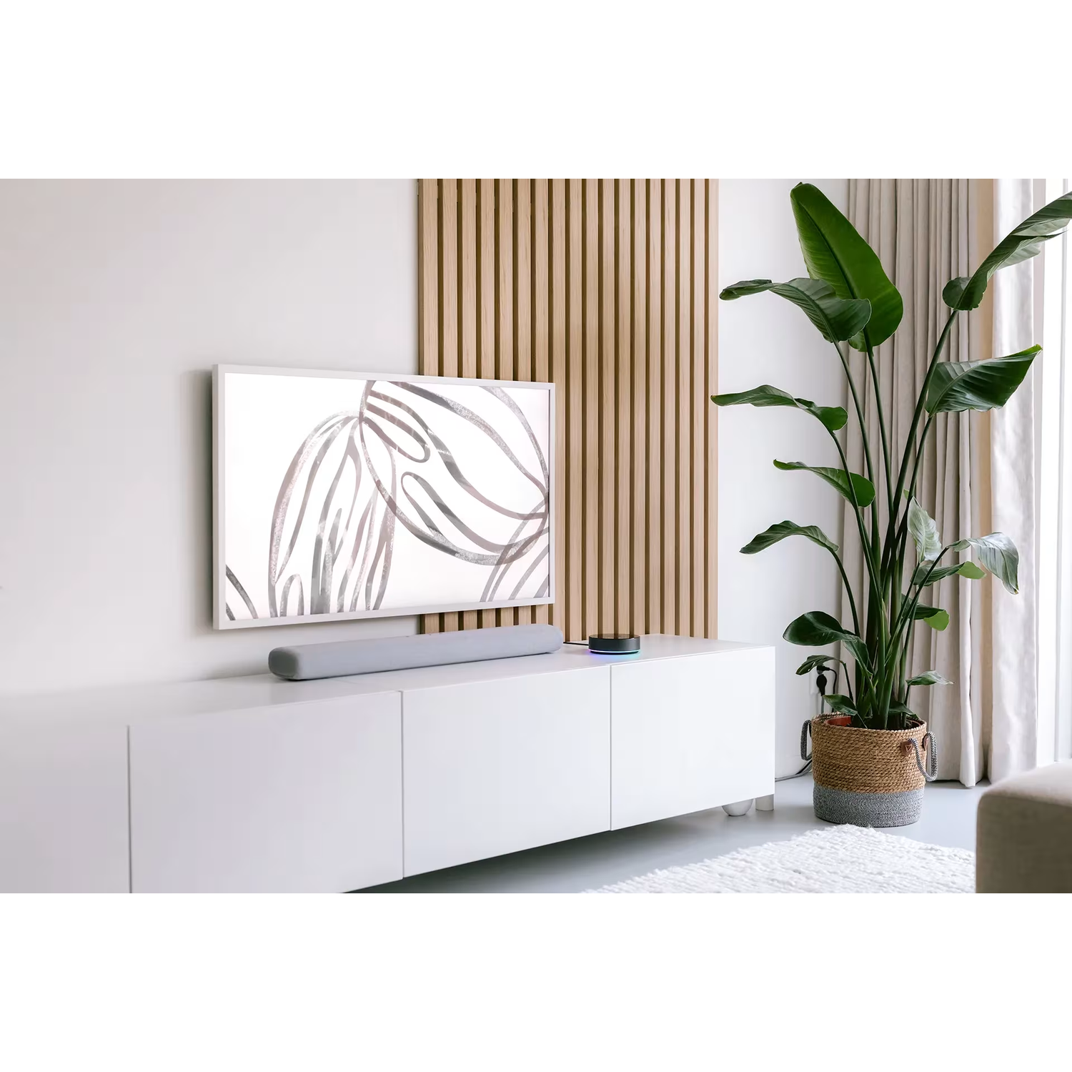 A minimalist living room with a TV, soundbar, smart speaker, plant, and slatted wall.