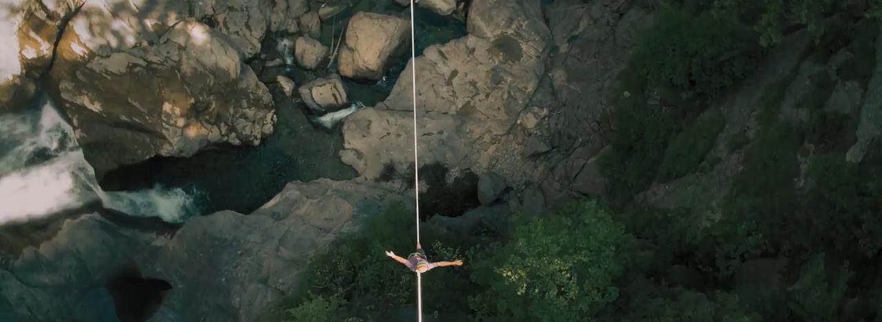 Eine Person springt mit dem Bungee über eine felsige Schlucht mit einem Fluss darunter.