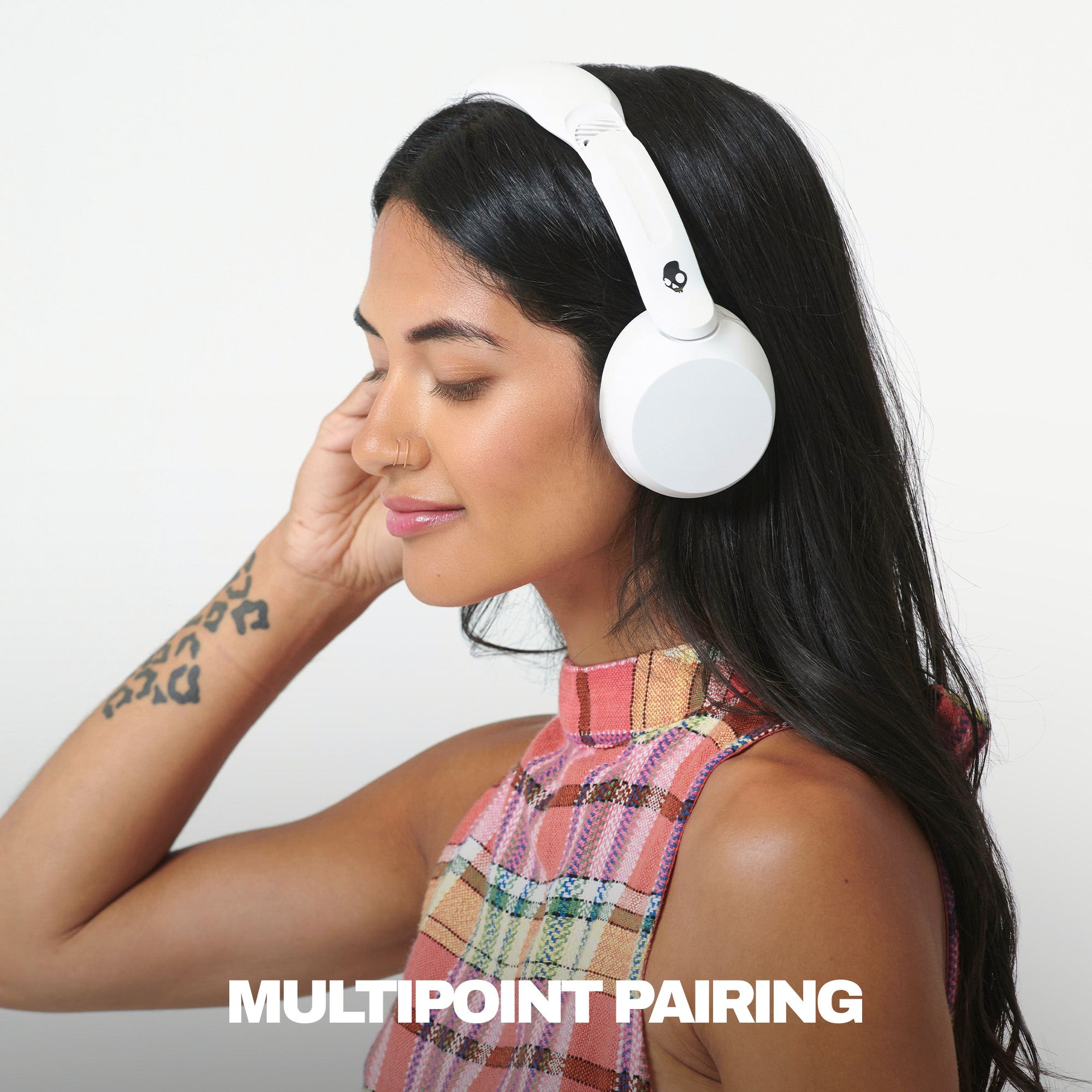 Frau mit weißen Kopfhörern und bunt kariertem Oberteil, Text 'MULTIPOINT PAIRING'.