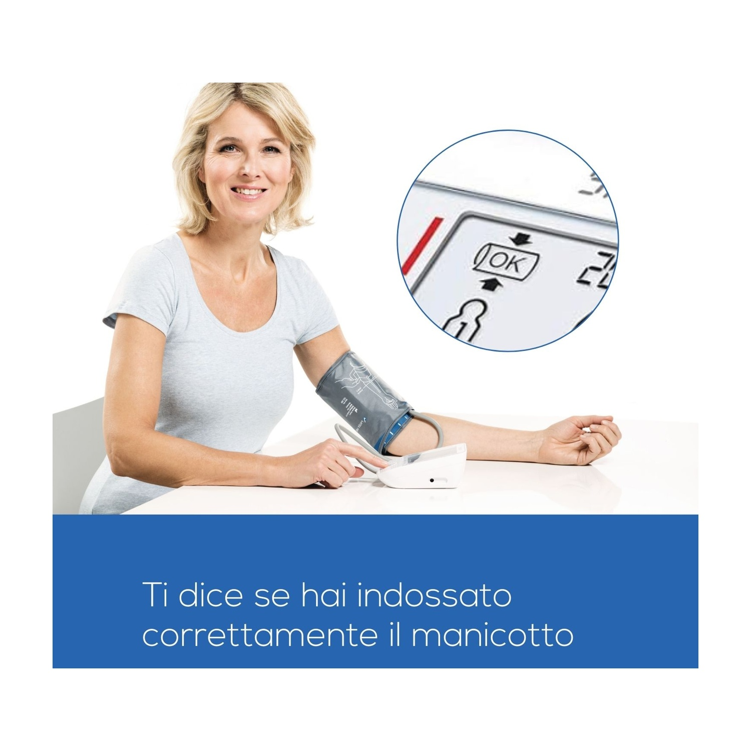 Una donna con un bracciale per la pressione sanguigna sul braccio è seduta e sorride.