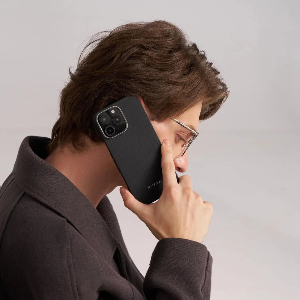 Mężczyzna w okularach rozmawia przez telefon, trzymając czarny telefon z aparatem.