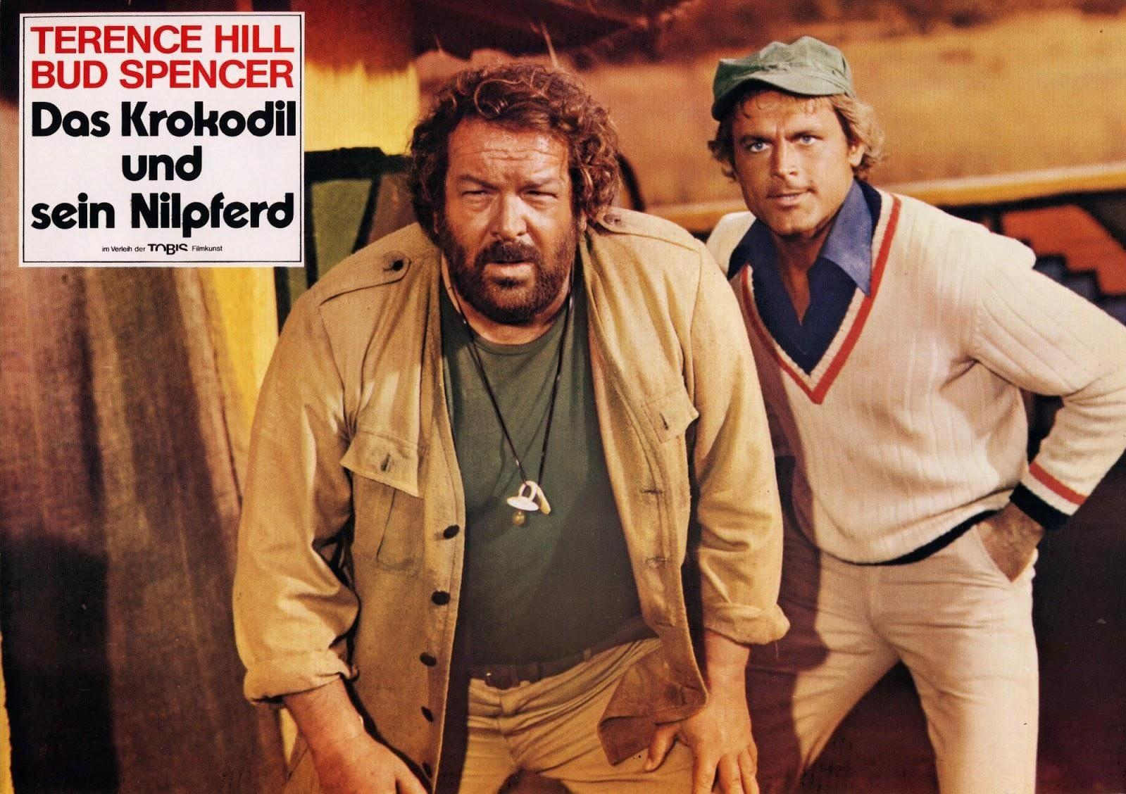 Zwei Männer stehen vor einem Filmplakat. Einer trägt eine beige Jacke, der andere einen Pullover.