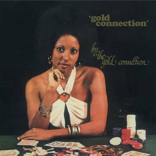 Frau mit Afro-Haar sitzt an einem Pokertisch mit Karten und Chips. Text: 'gold connection'.