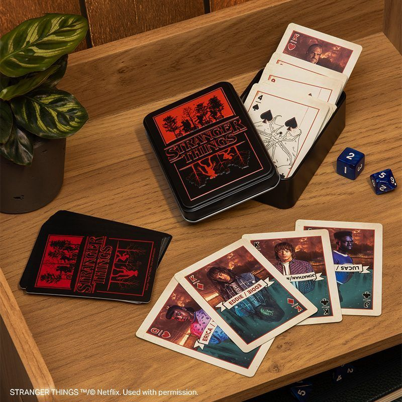 Stranger Things játékkártyák és egy fémdoboz fadobozon, kockákkal.