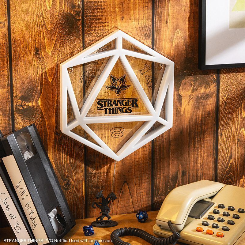 Stranger Things D20 kockadísz falon, VHS kazettákkal és régi telefonnal.