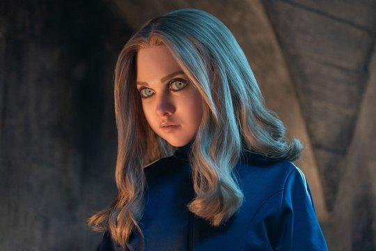 Ein junges Mädchen mit blonden Haaren und blauen Augen blickt nach links.