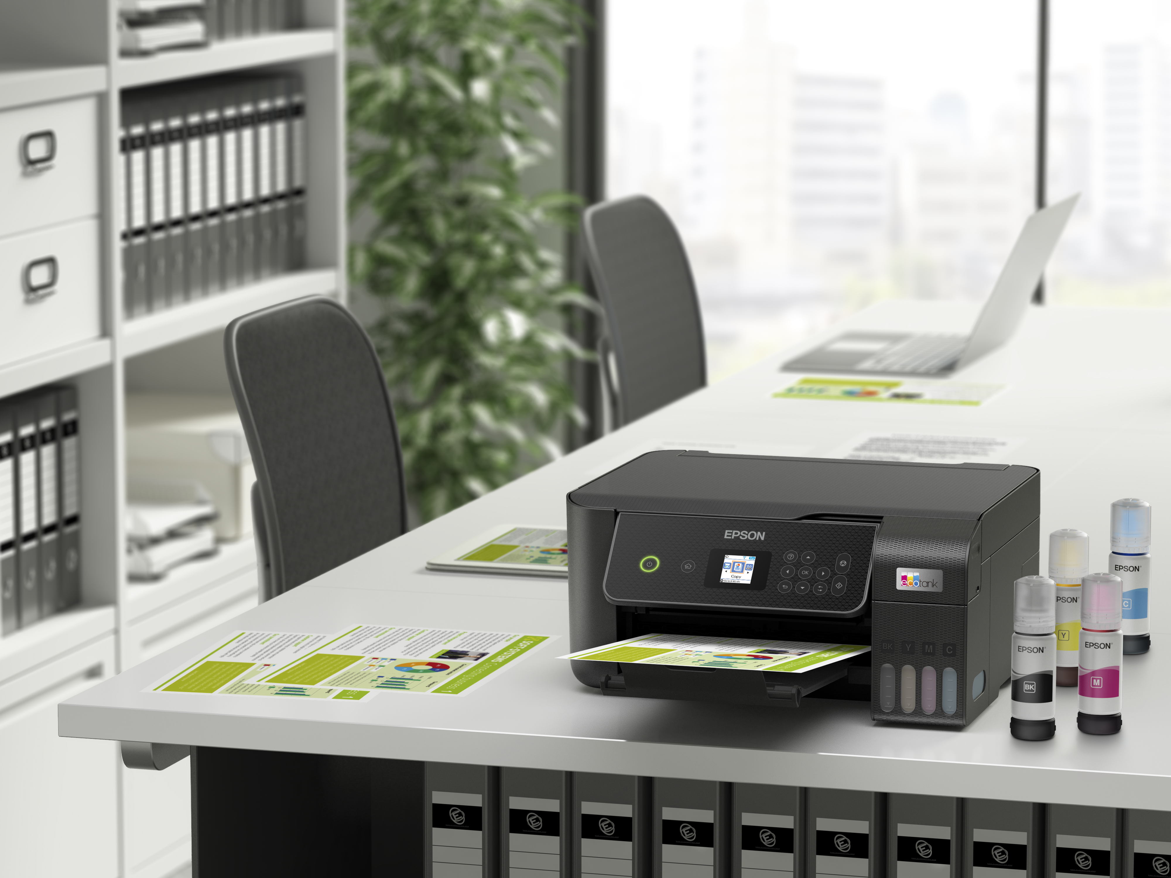 Una stampante Epson con bottiglie d'inchiostro su una scrivania, con forniture per ufficio e sedie sullo sfondo.