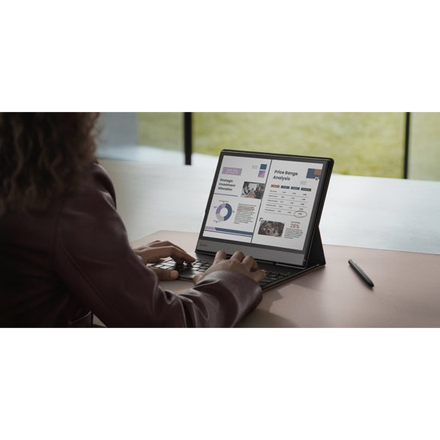 Person typing on a laptop displaying charts and graphs. A stylus rests nearby.