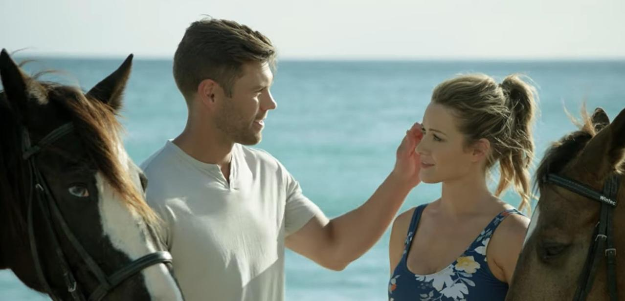 Mann und Frau mit Pferden am Strand, Meer im Hintergrund.