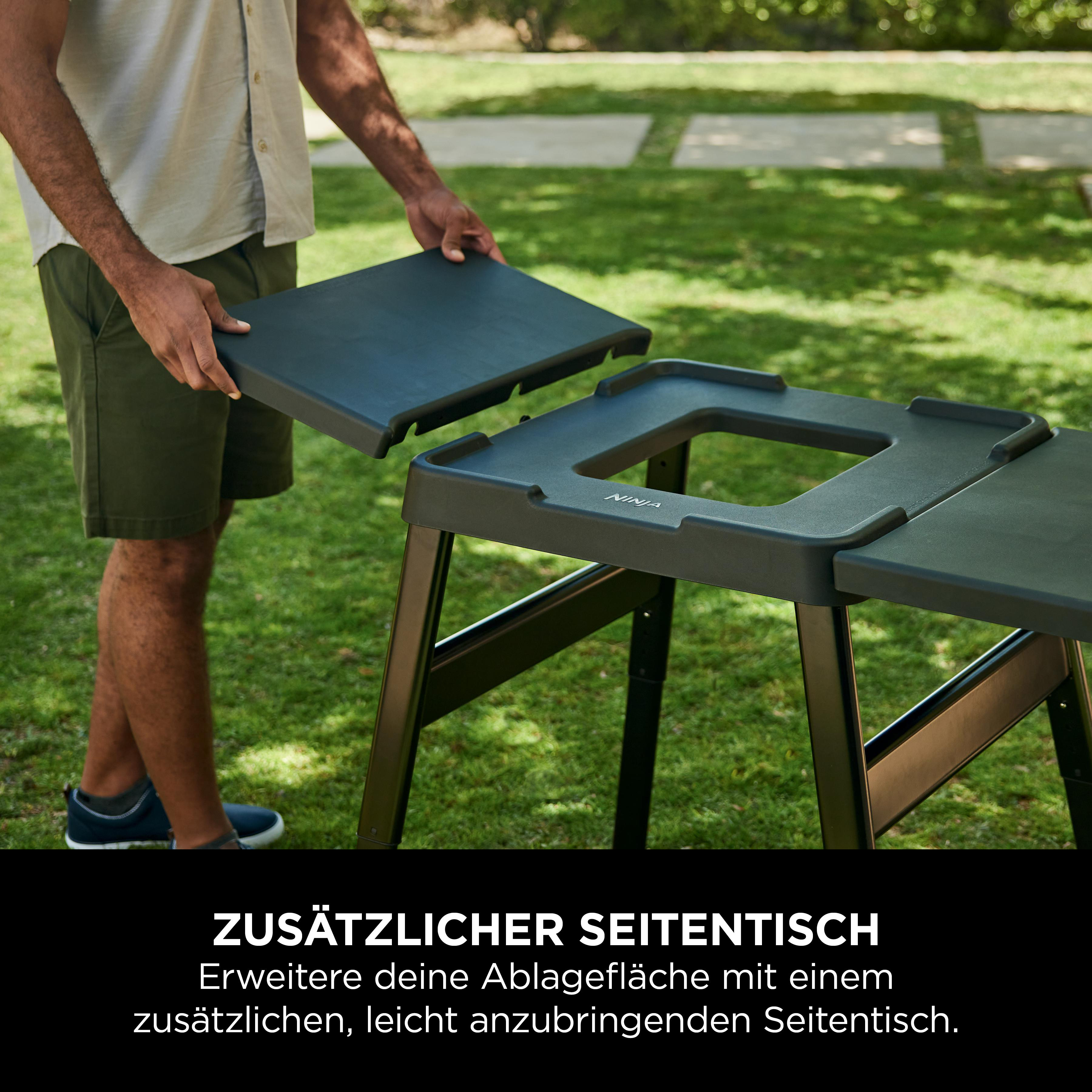 Mann montiert schwarzen Ninja-Seitentisch im Garten.