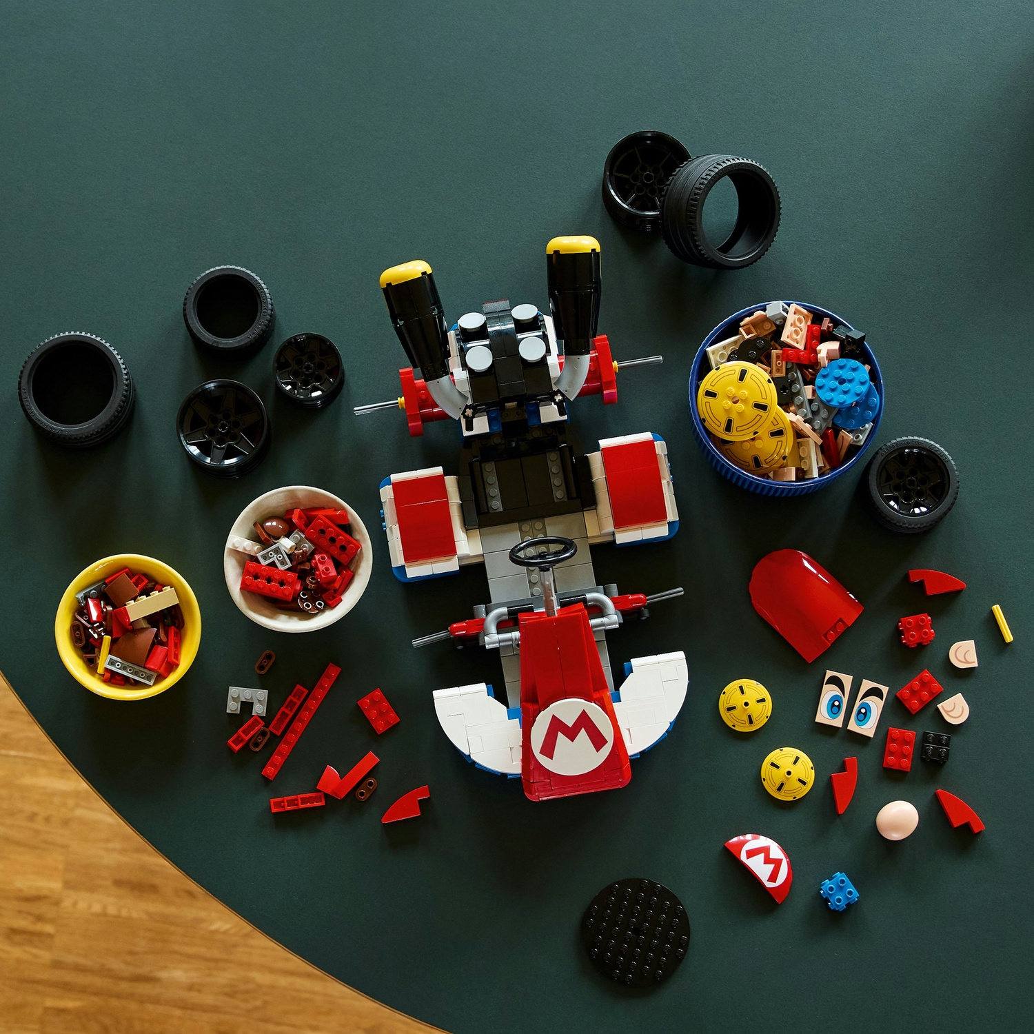 Costruzione Lego Mario Kart con pezzi sparsi: ruote, mattoncini e parti.