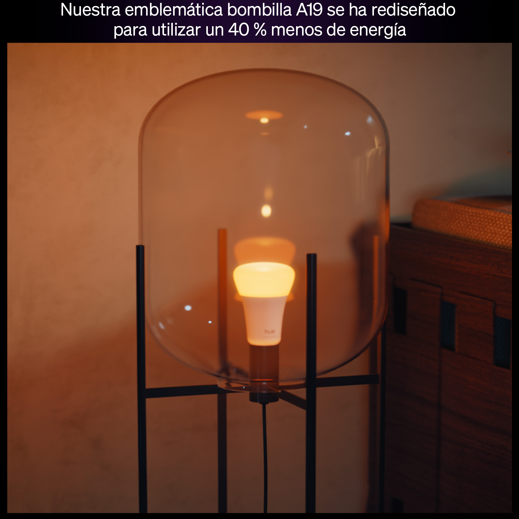 Una bombilla blanca encendida con logo Hue sobre un soporte oscuro bajo una cúpula de cristal.