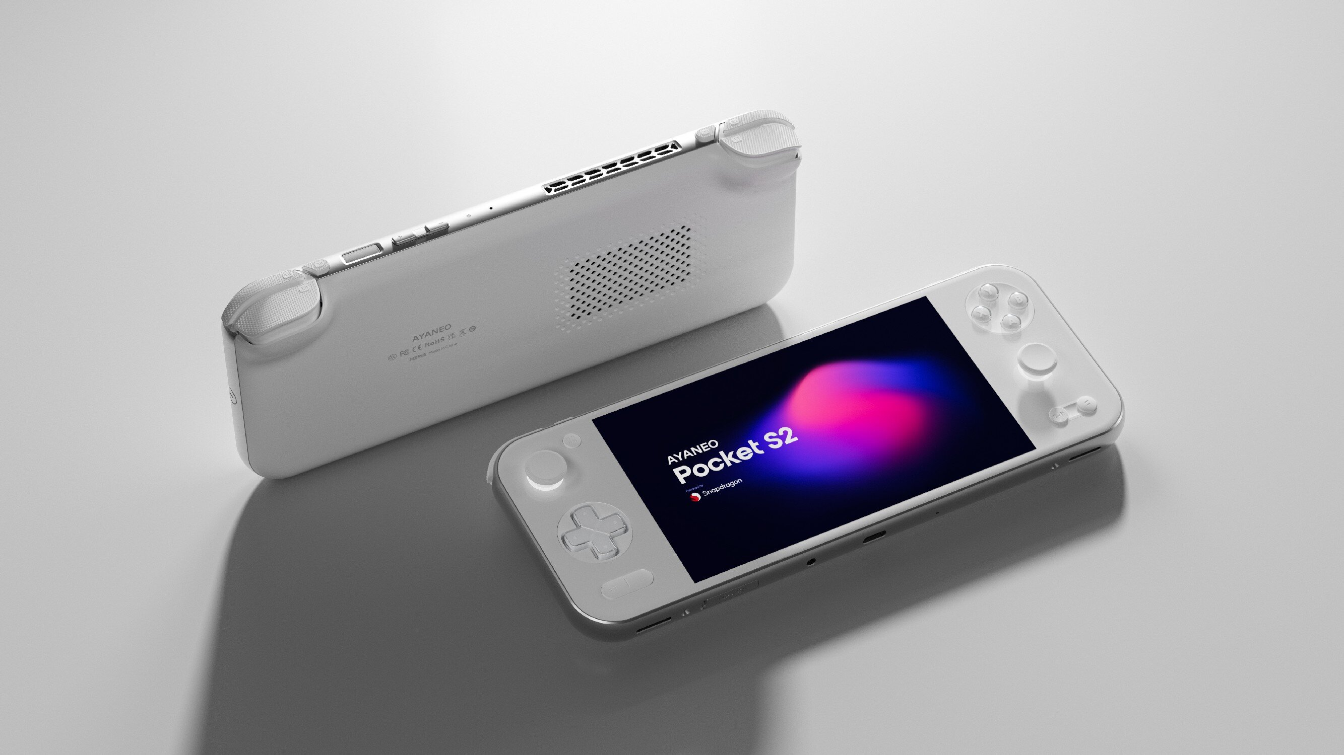 Dwie białe konsole przenośne AYANEO Pocket S2 leżą obok siebie na szarej powierzchni.