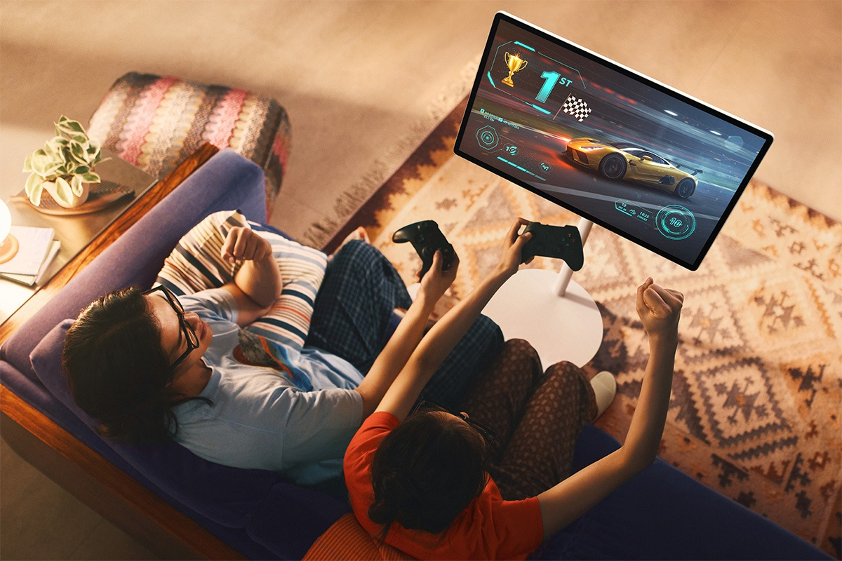 Due persone giocano a un gioco di corse sullo schermo, mani alzate con i controller.