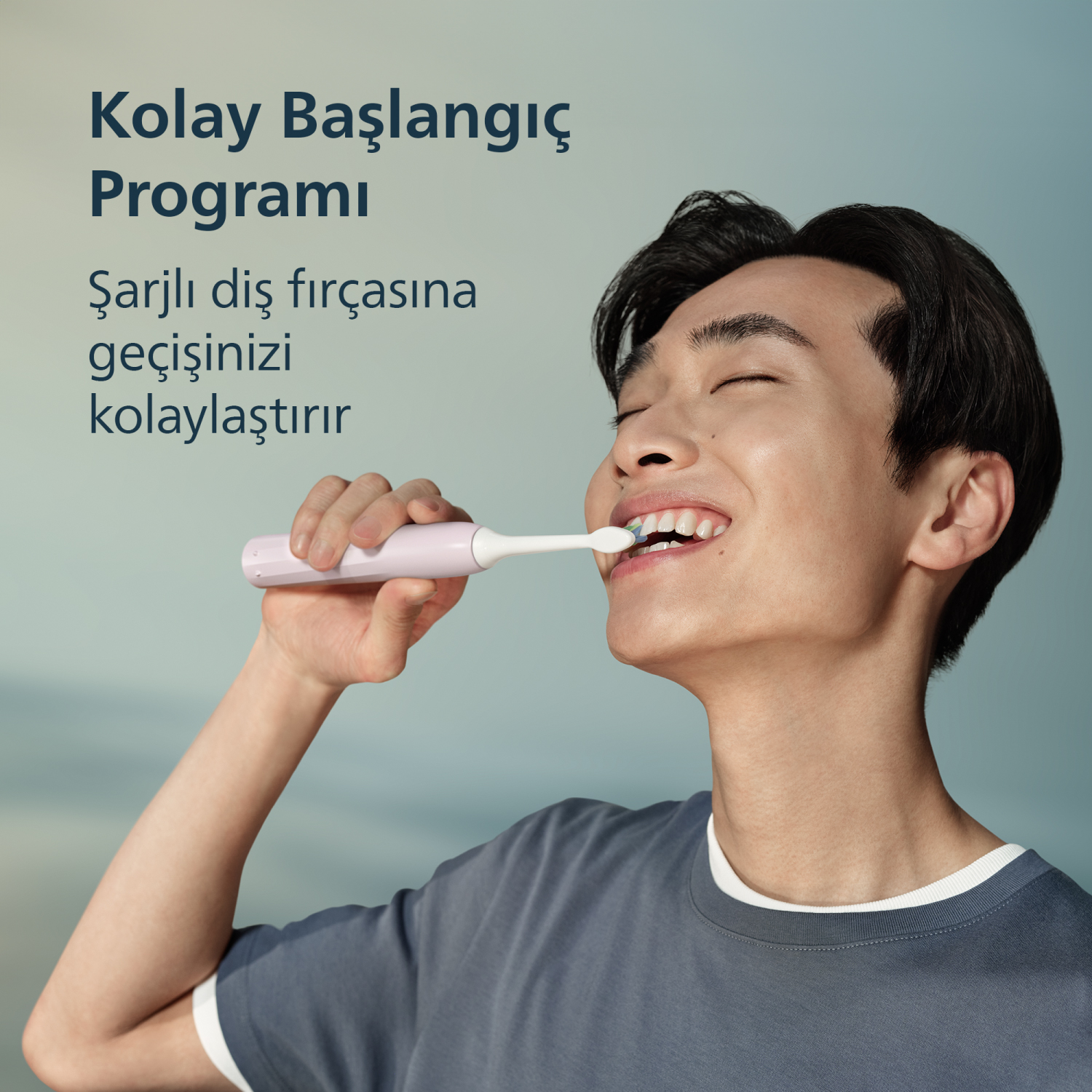 Genç bir adam açık pembe diş fırçasıyla dişlerini fırçalıyor.