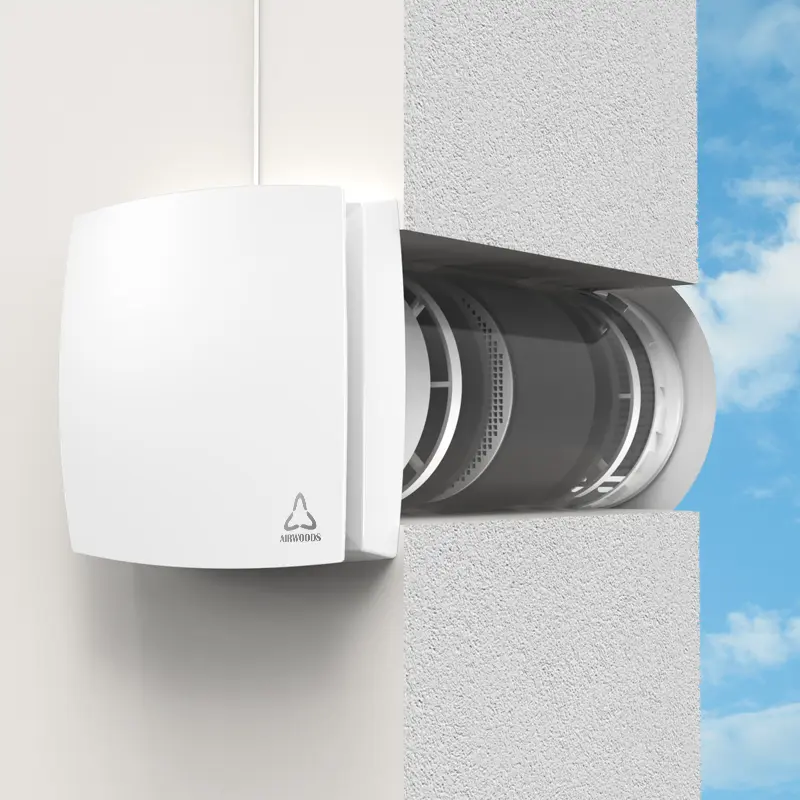 Egy fehér szellőzőventilátor van a falra szerelve. A falon keresztül látszik a ventilátor belseje.