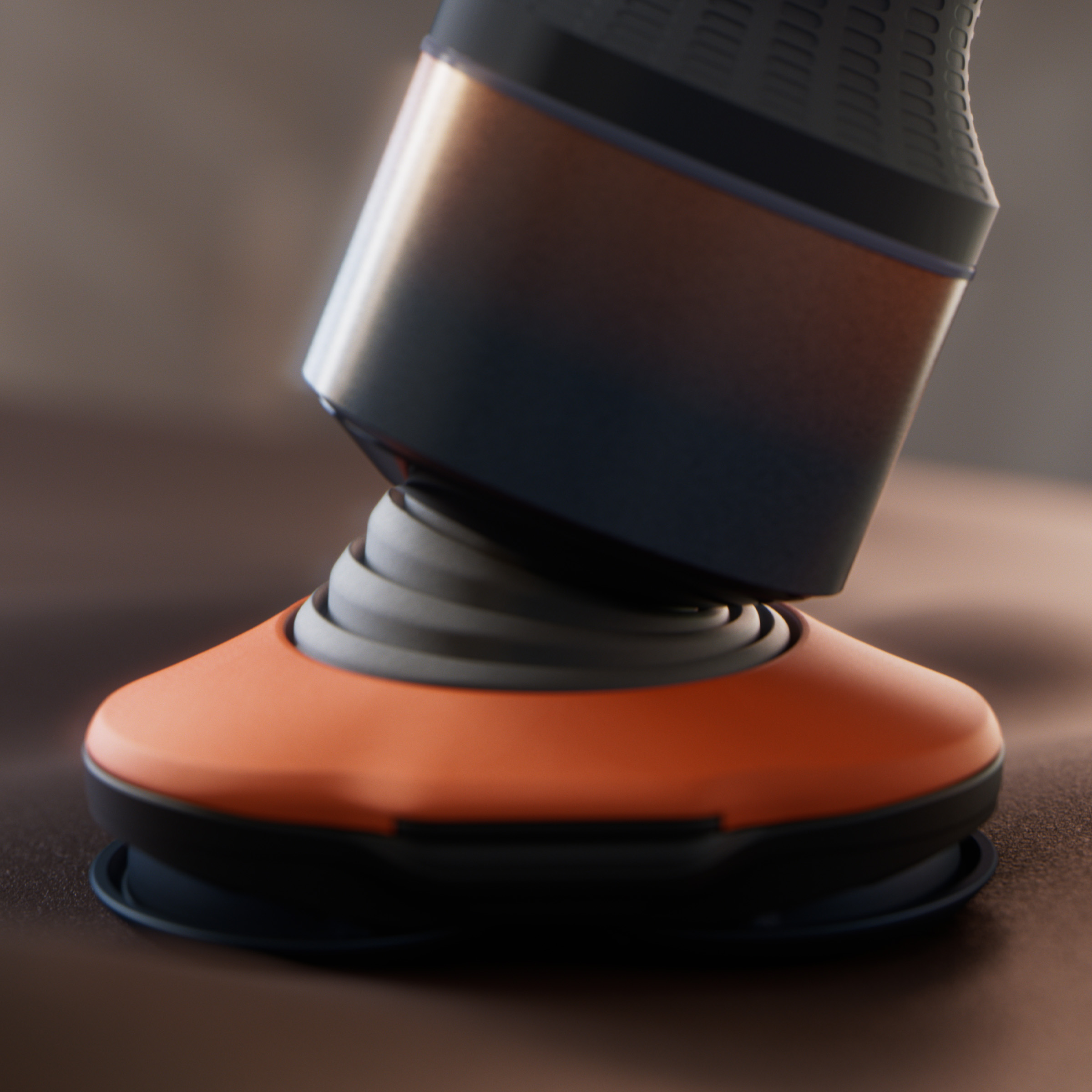 Pomarańczowo-czarne urządzenie ze sprężynowym zawieszeniem spiralnym na brązowej powierzchni.