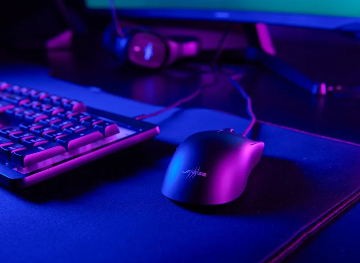 Eine Gaming-Tastatur und eine Maus auf einer schwarzen Matte, beleuchtet in Blau und Lila.