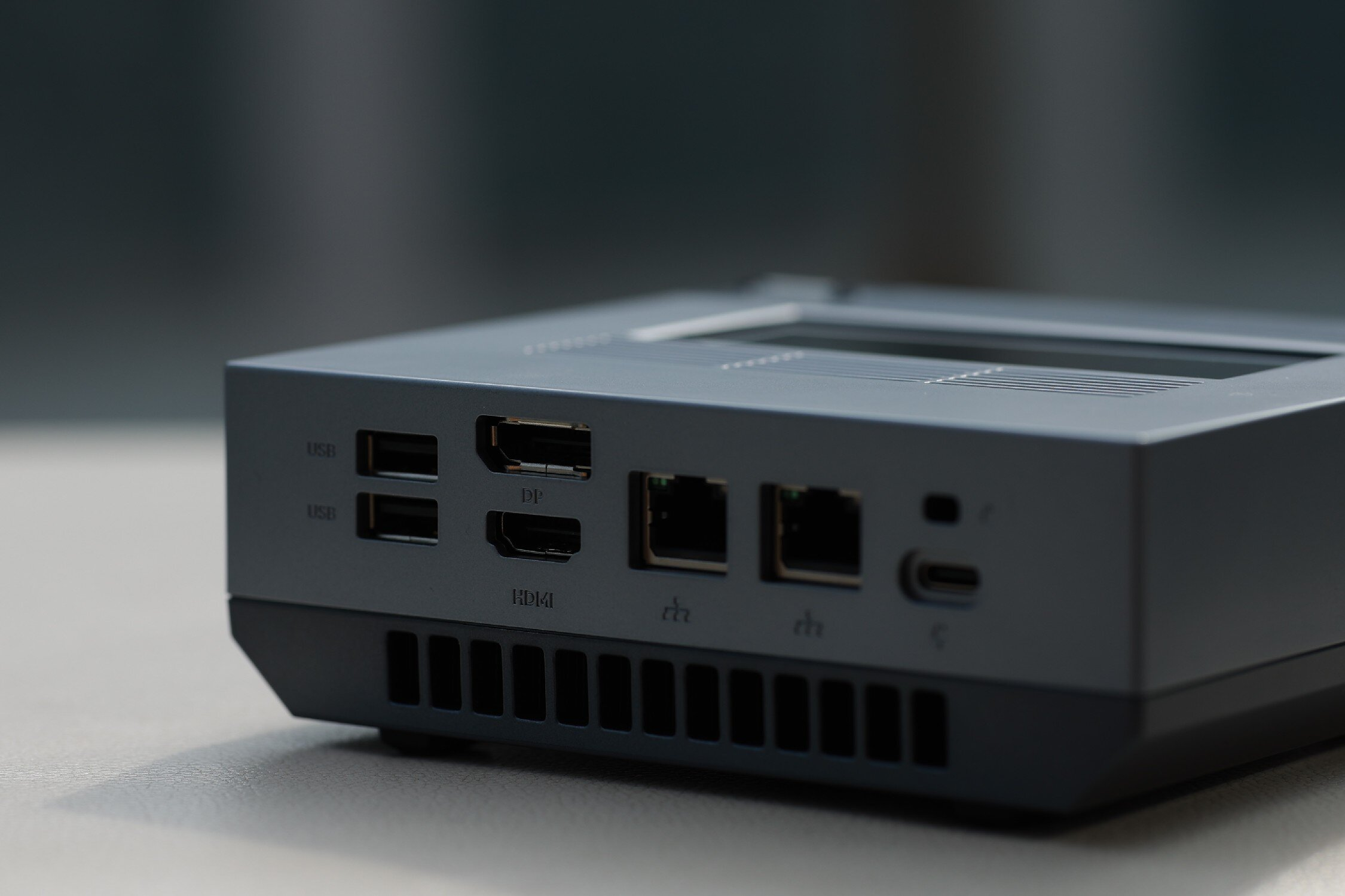 Tylny panel szarego mini PC z portami USB, DP, HDMI, Ethernet i USB-C.