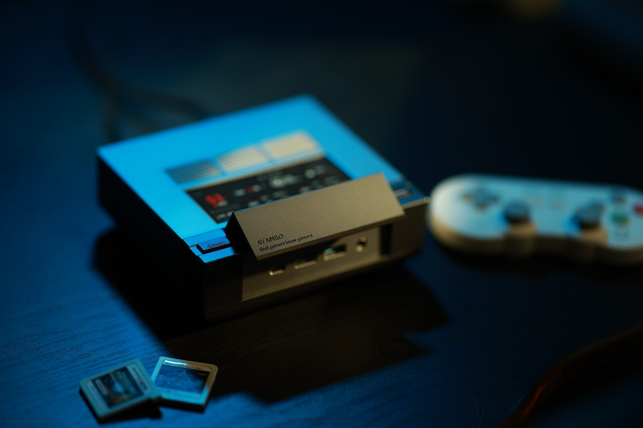 Niebieskie urządzenie do gier retro z kontrolerem i dwiema kartami.