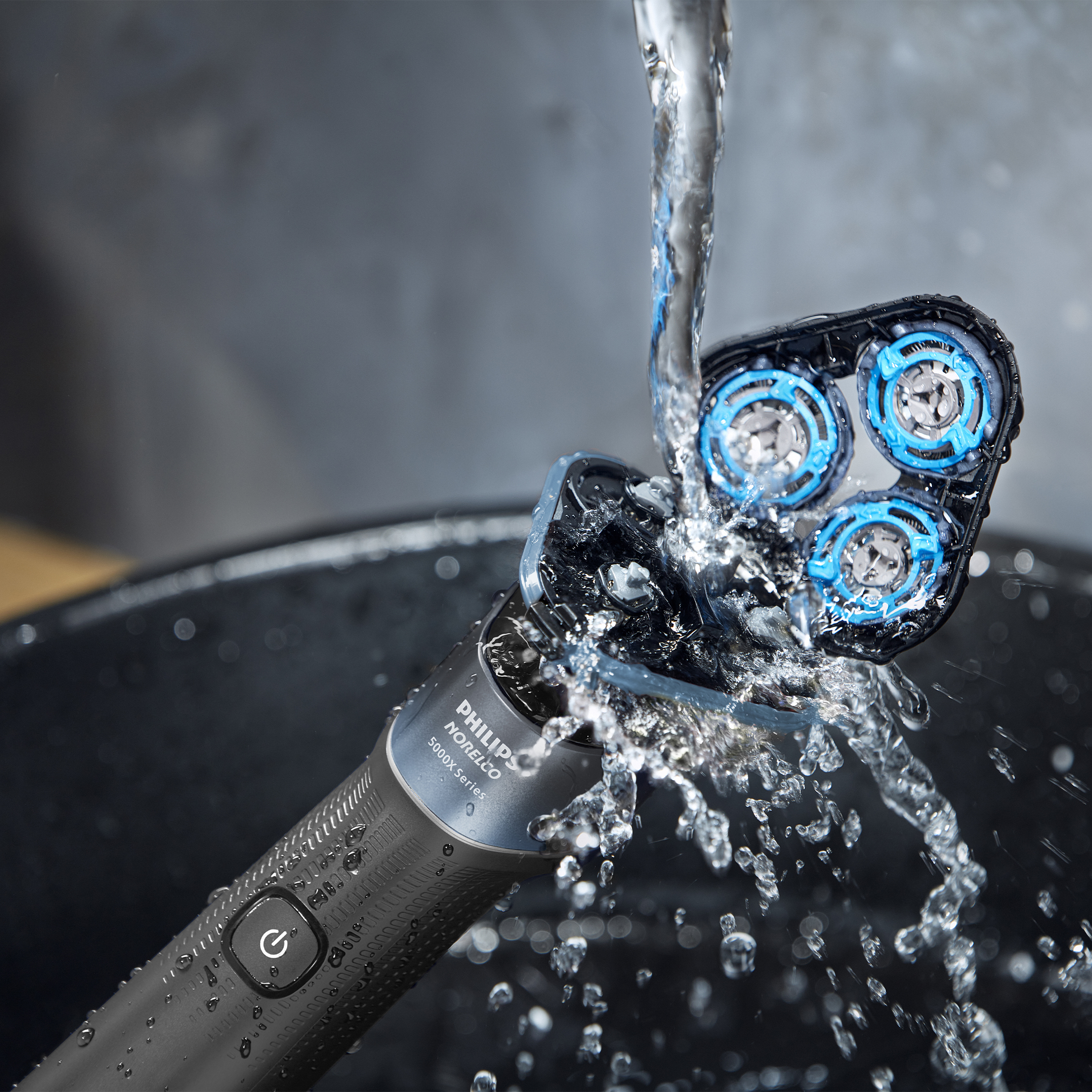 Golenie Philips jest płukane pod bieżącą wodą. Główki golarki są mokre.