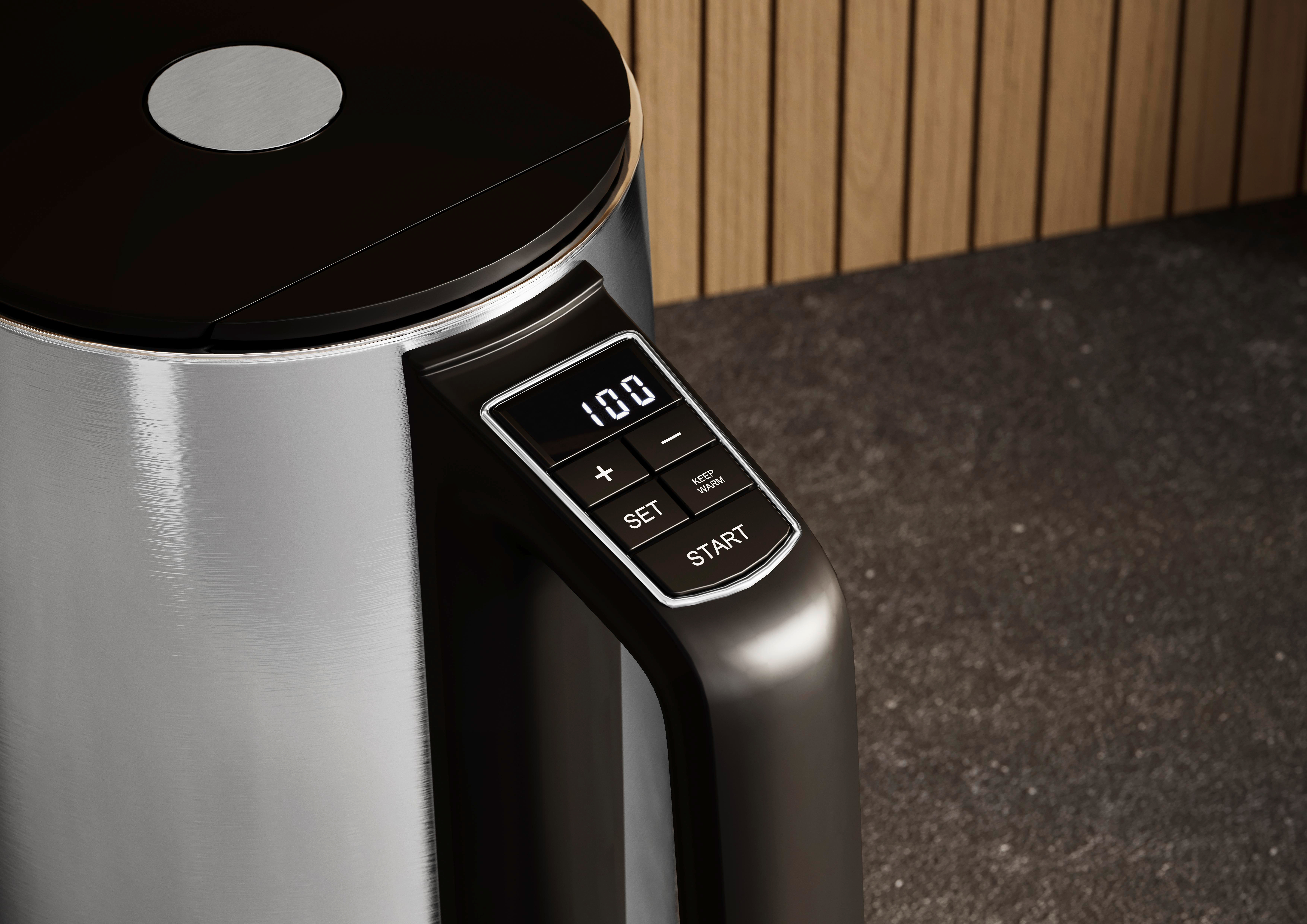 Nahaufnahme eines Wasserkochers mit digitaler Anzeige von 100, Tasten und Holz Hintergrund.